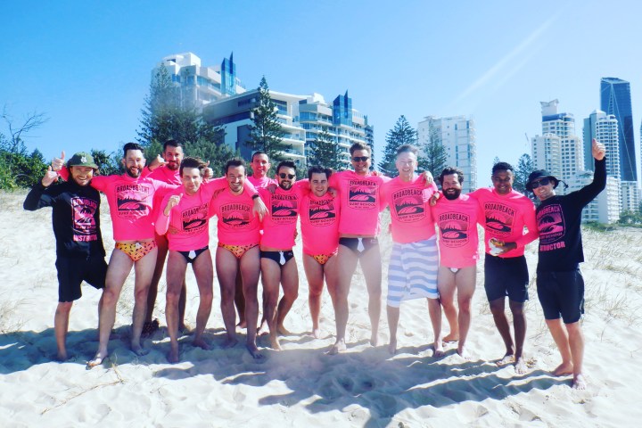 a group of people standing on a beach posing for the camera