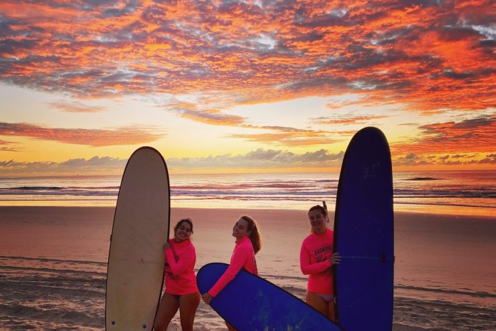 people walking on a beach holding a surf board
