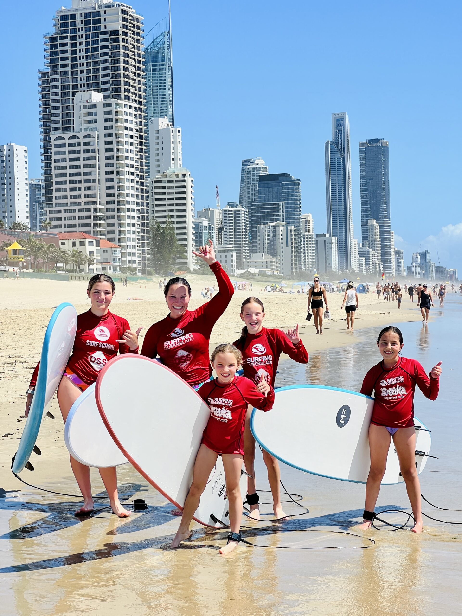 a group of people standing on a beach holding a surfboard